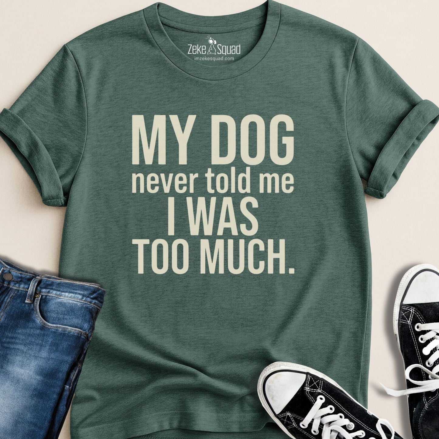 Green t-shirt with humorous text design, paired with jeans and sneakers on a neutral background.