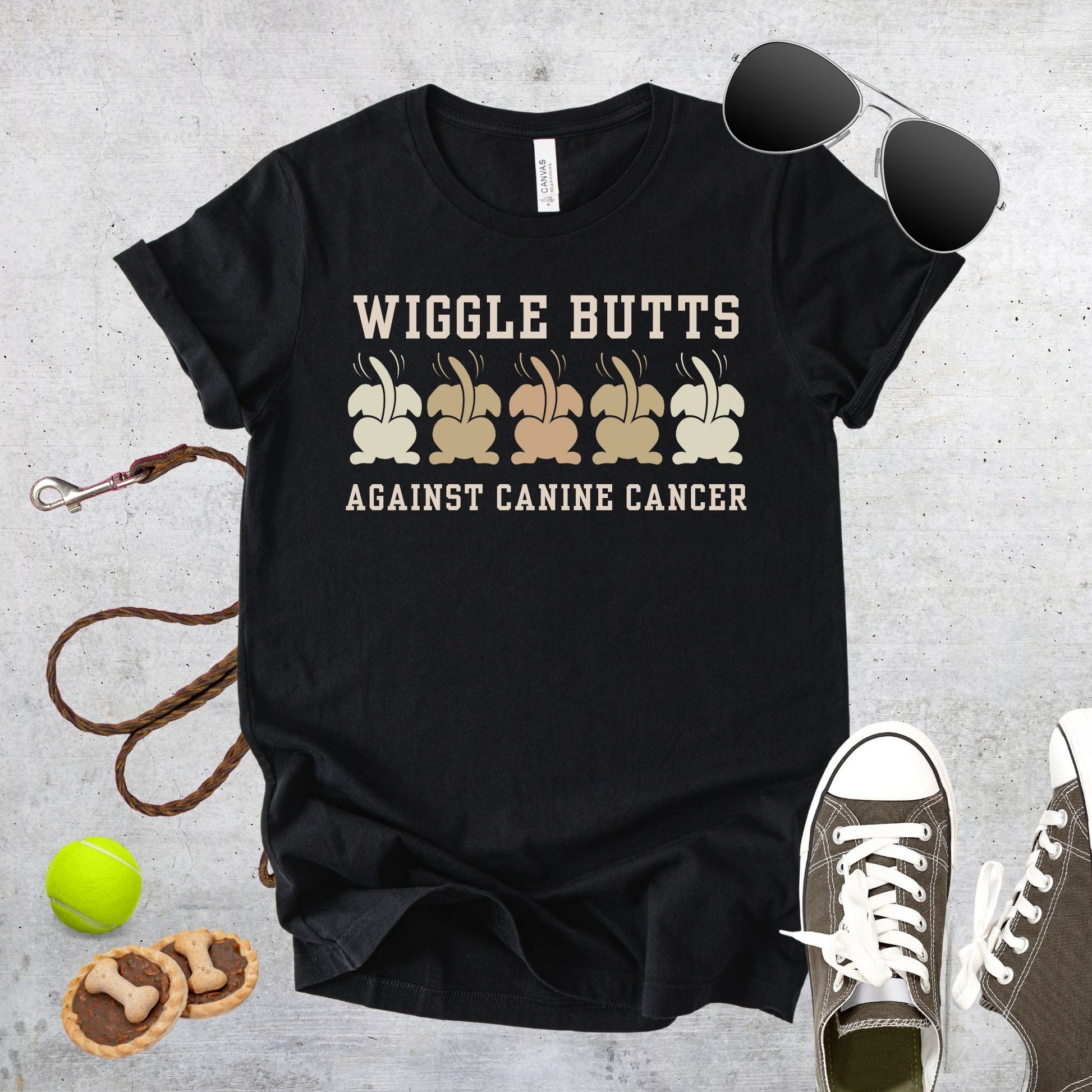 Unisex Zeke Squad T-shirt with the quote “Wiggle Butts Against Canine Cancer” featuring a row of dog booties.
