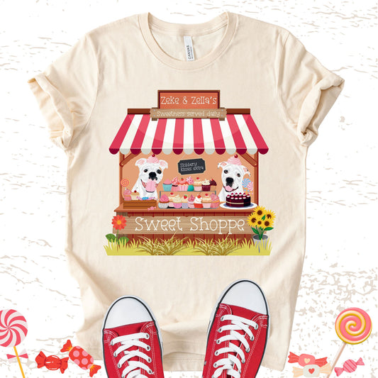 Unisex Zeke Squad T-shirt with a graphic of Zeke and Zella behind a candy shop counter and a sign that says “Slobbery kisses extra.”